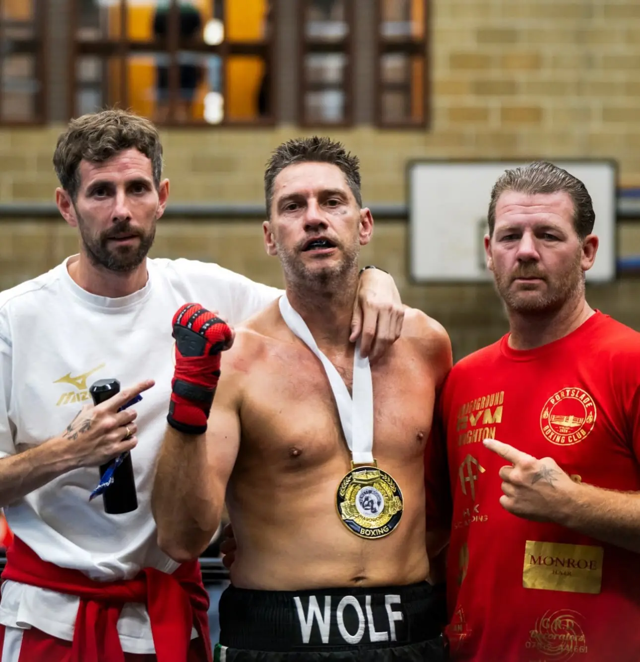 A boxer with a medal round his neck between two coaches
