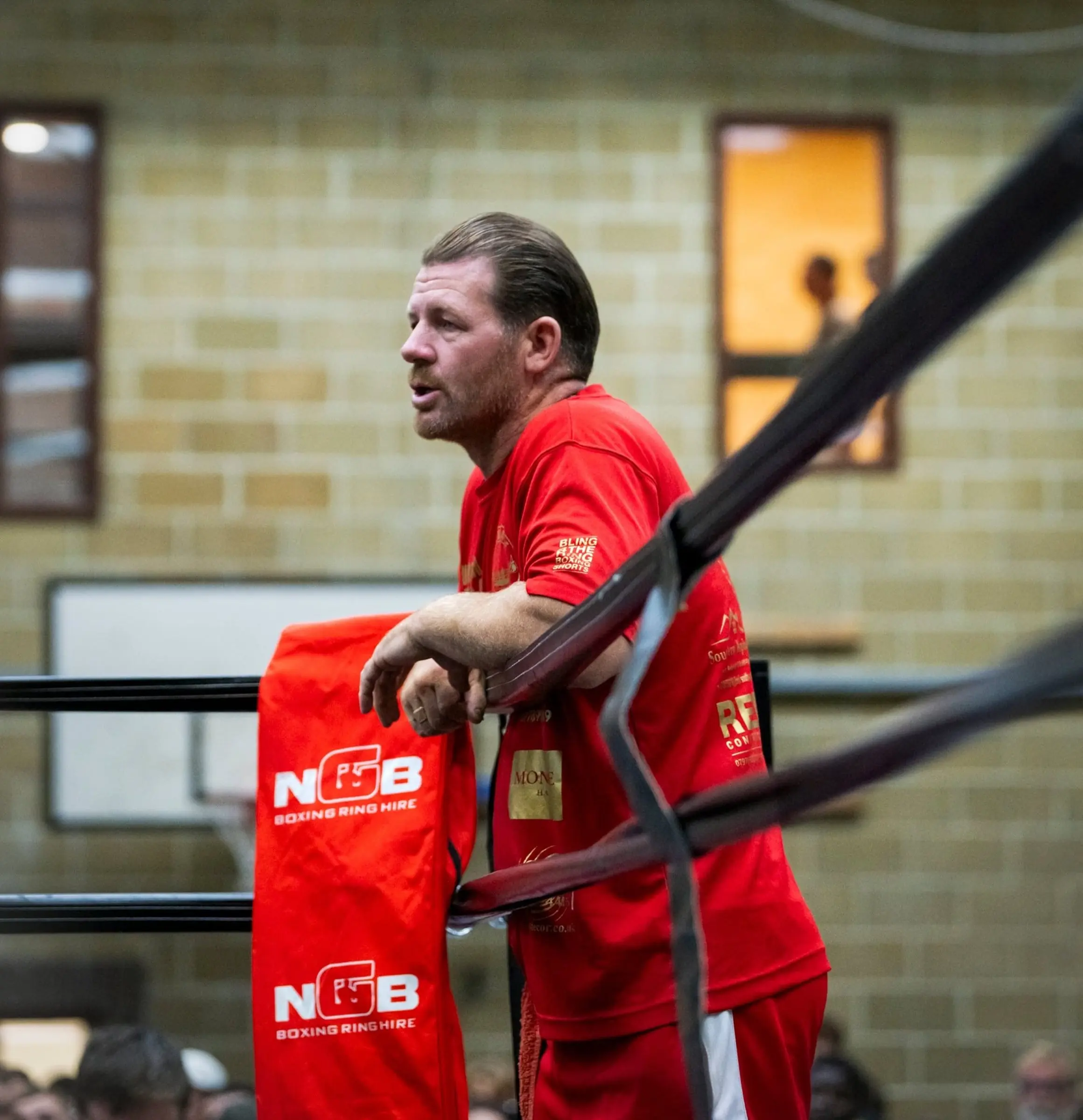 A coach leaning on the ring corner during a fight